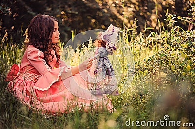 Child girl dressed as fairytale princess playing with doll in summer forest Stock Photo