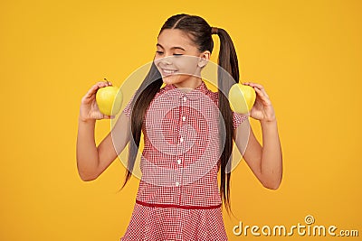 Child girl eating an apple over yellow background. Tennager with fruit. Happy teenager, positive and smiling Stock Photo