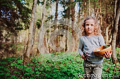 Child girl exploring nature in early spring forest. Kids learning to love nature. Teaching children about seasons changing. Stock Photo