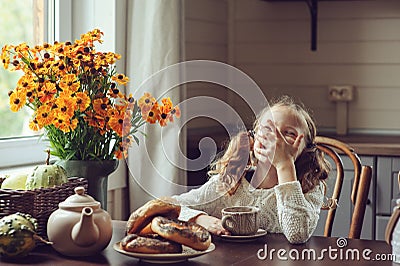 Child girl having breakfast at home in autumn morning. Real life cozy modern interior in country house Stock Photo