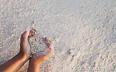Child girl holding sand make heart shape in hands and playing on the beach Stock Photo