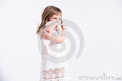 Child girl hugging her pink teddy bunny on white background. Cute girl with her toy Stock Photo