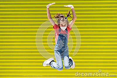 Child girl jumping wearing a protection mask against coronavirus Stock Photo