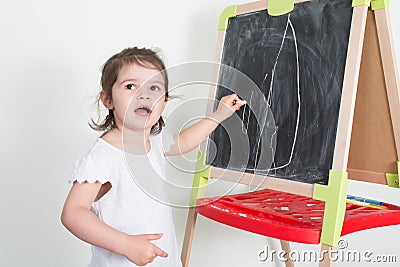 Child girl makes chalk drawings on a chalkboard Stock Photo