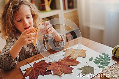 Child girl making herbarium at home, autumn seasonal crafts Stock Photo