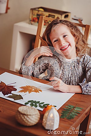 Child girl making herbarium at home, autumn seasonal crafts Stock Photo