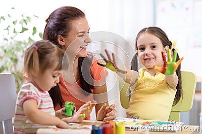 Child girl with painted hands. Kids drawing and coloring with teacher in daycare center. Stock Photo