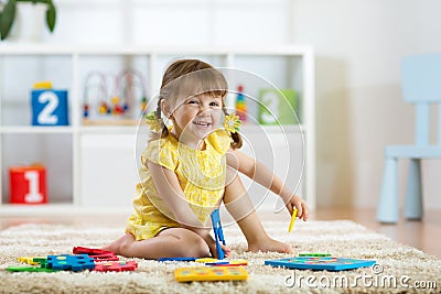 Child girl playing indoors with sorter toy sitting on soft carpet Stock Photo