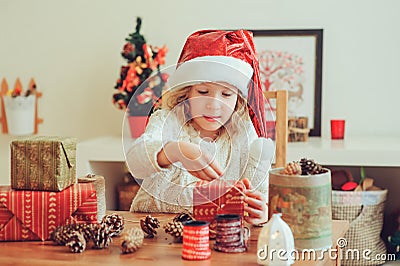 Child girl preparing gifts for christmas at home, cozy holiday interior Stock Photo