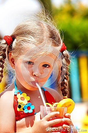 Child girl in red bikini drink orange juice. Stock Photo