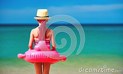 Child girl stands with her back with a Flamingo lifeline on beach Stock Photo