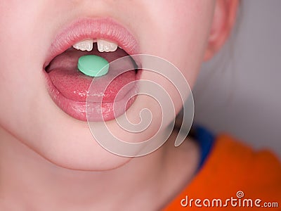 Child girl takes green pill. Teatment. Medicine eating. Stock Photo
