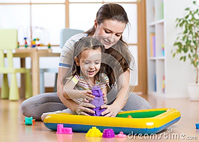 Child girl and woman mould with kinetic sand in playschool or daycare Stock Photo