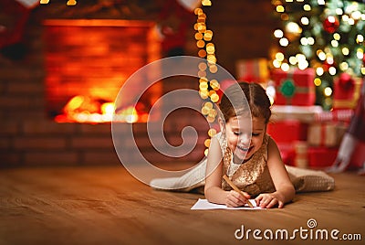 Child girl writing letter santa home near Christmas tree Stock Photo