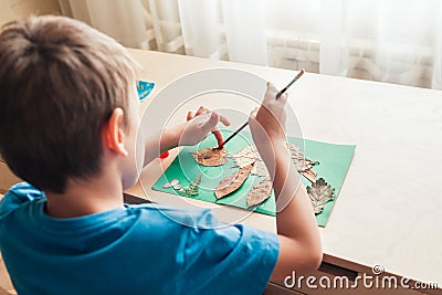 Child glues an applique made of autumn leaves Stock Photo