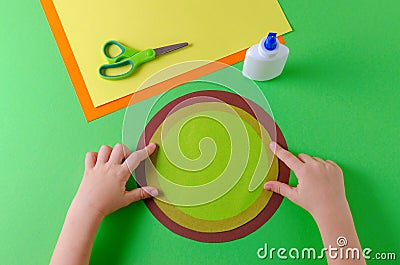 Child glues two circles with color paper, glue and scissors Stock Photo