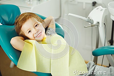 Child in good mood sitting on chair and without fear waiting dentist. Young boy is going to treat teeth. caries Stock Photo