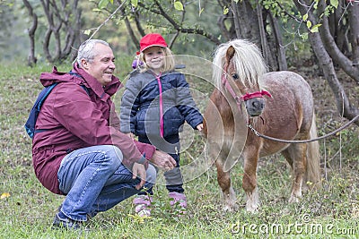 Child, grandfather and pony Stock Photo