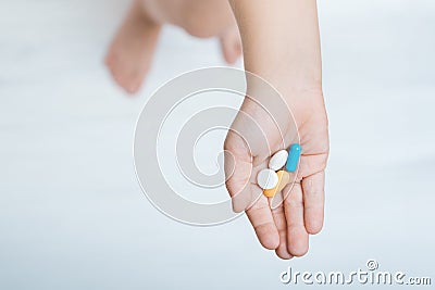 Child hand with colorful pills on white background top view. Vitamins for children Stock Photo