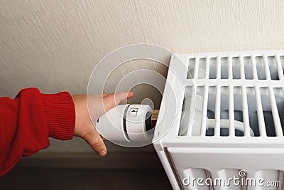 Child hand controls thermostatic knob of heating radiator Stock Photo