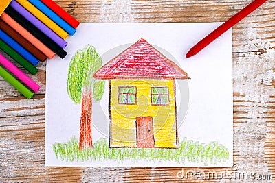 Child hand drawing House with wax crayons. Wood background Stock Photo