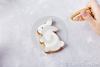 Child hand holds carrot cookie and rabbit cookie backdrop. Happy Easter background Stock Photo