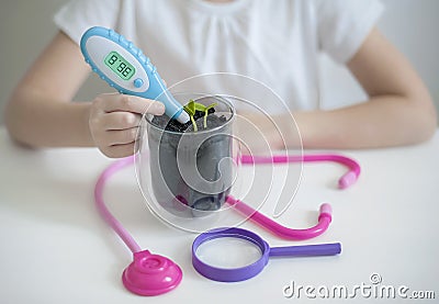 Child hand measuring temperature with thermometer. Caring for a new life. Save earth from global warming. Stock Photo