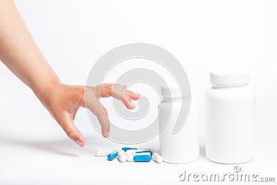 Child hand piccking pills on a white. Little hand takes drugs from container Stock Photo