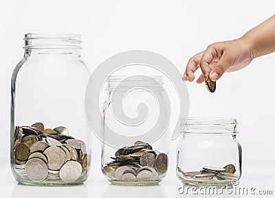 Child hand putting a coin into glass bottle, future saving concept Stock Photo