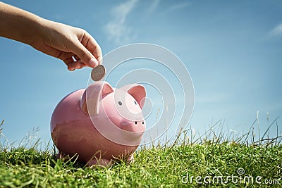 Child hand saving money in piggy bank Stock Photo