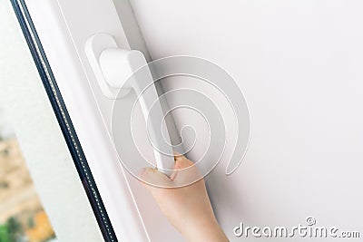 Child Hand Trying To Open A Window Handle Of A Closed White Window - Prevent Child Hazard Concept Stock Photo