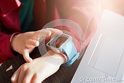 Child hand wearing smart watch. Wearable gadget concept. Little boy using smart watch while siting at the table and working with Stock Photo