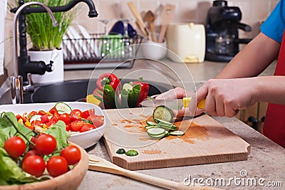 Child hands chopping vegetables on cutting board - slicing the c Stock Photo