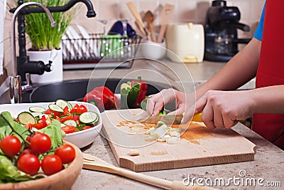 Child hands chopping vegetables on cutting board - the spring on Stock Photo