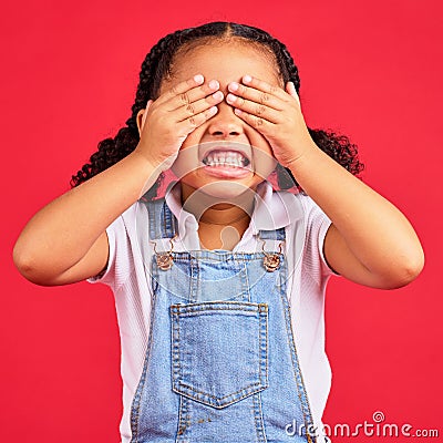 Child, hands and eyes cover on isolated red background with angry, mad or stubborn facial expression. Girl, kid and Stock Photo
