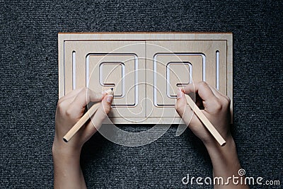 Child hands drawing lines in two-sided wooden stencil labyrinth Stock Photo