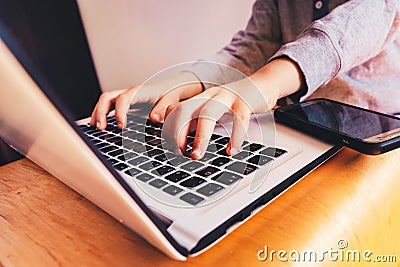 Child hands on laptop computer keyboard next to a mobile phone to do business Stock Photo