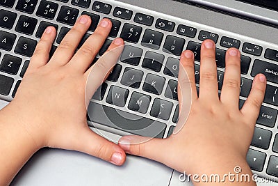 Child hands press buttons on laptop keyboard, child learning and playing on computer Stock Photo