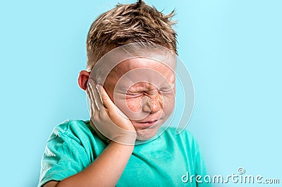 Child has earache. School boy has sore ear. Little kid covered ear with hand and closed eyes. Kid suffering from otitis Stock Photo