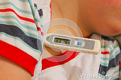 The child has a fever. The thermometer shows 37.7. The child fell ill, a thermometer under his arm. Stock Photo