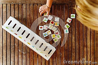 Child having fun with an educational wooden game at school, to make pairs, useful to improve the memory and dexterity of their Stock Photo