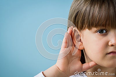 Little girl with hearing problem on light blue background. Close up, copy space Stock Photo