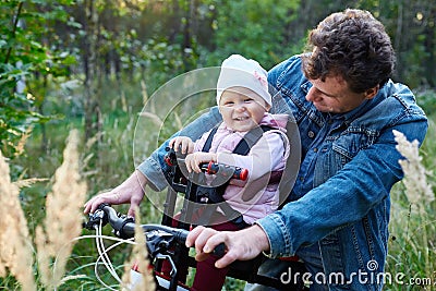 child and his father ride a bicycle using a child seat. The concept of family, and joint recreation. Stock Photo