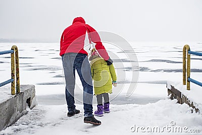 A child with his father walks in dangerous proximity to a frozen lake or river Stock Photo
