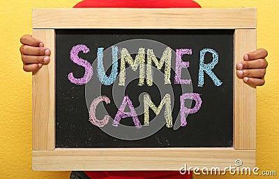 Child holding blackboard with words SUMMER CAMP Stock Photo