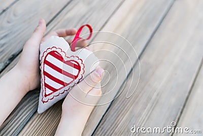 Child holding heart in hands over a wooden table Stock Photo