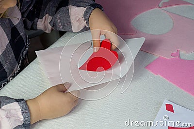 Child holding letter with red paper heart,love letter for Valentine& x27;s day,gift for Mothers day,little girl put Stock Photo