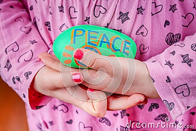 Child holding painted rock with the word Peace. Stock Photo