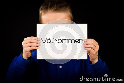 Child holding sign with Swedish word Valkommen - Welcome Stock Photo