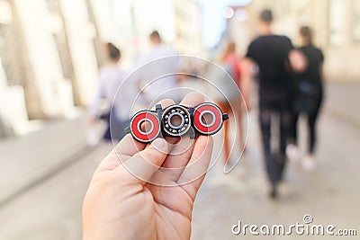 . Child holding unusual metal spinner at blurry people in the street background. Stock Photo